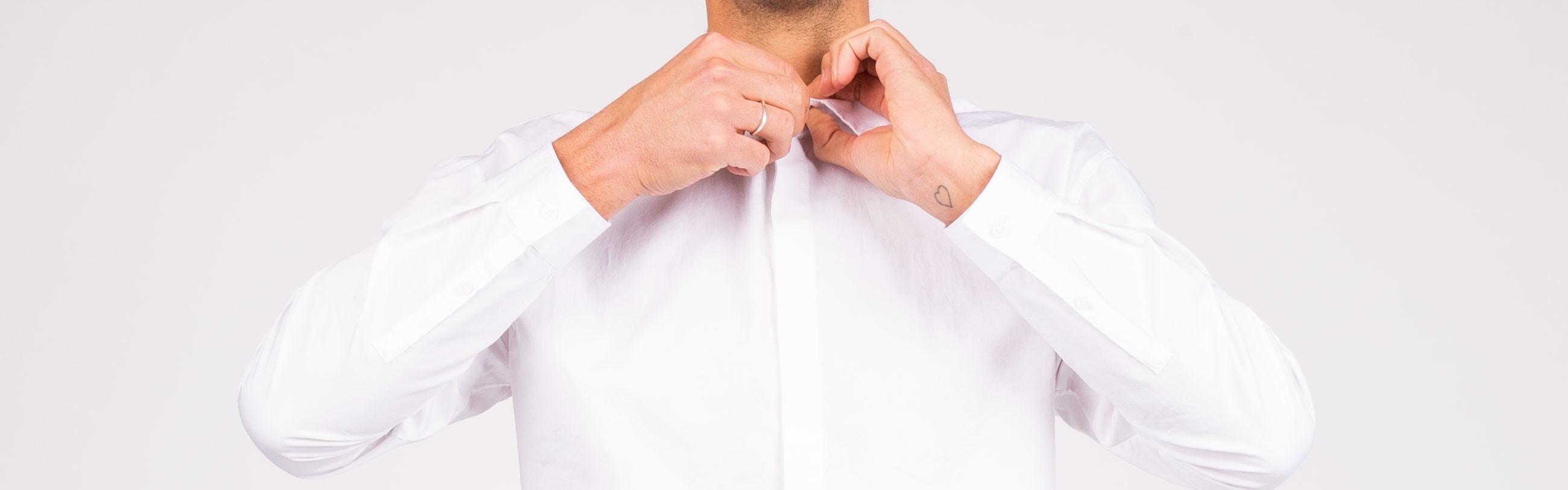 Man doing up collar of white shirt